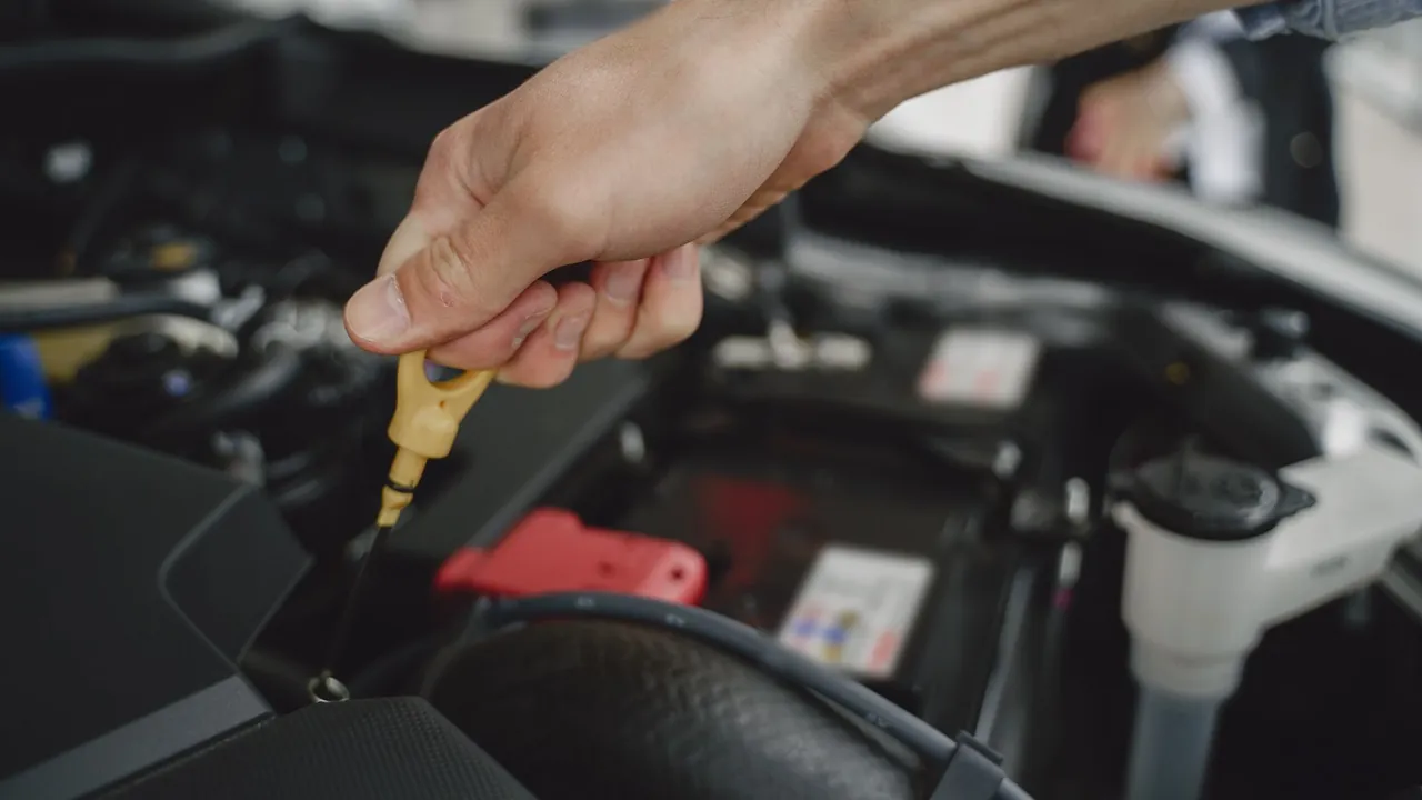 Motor yağı seviyesini kontrol etmek için yağ çubuğunu çeken el
